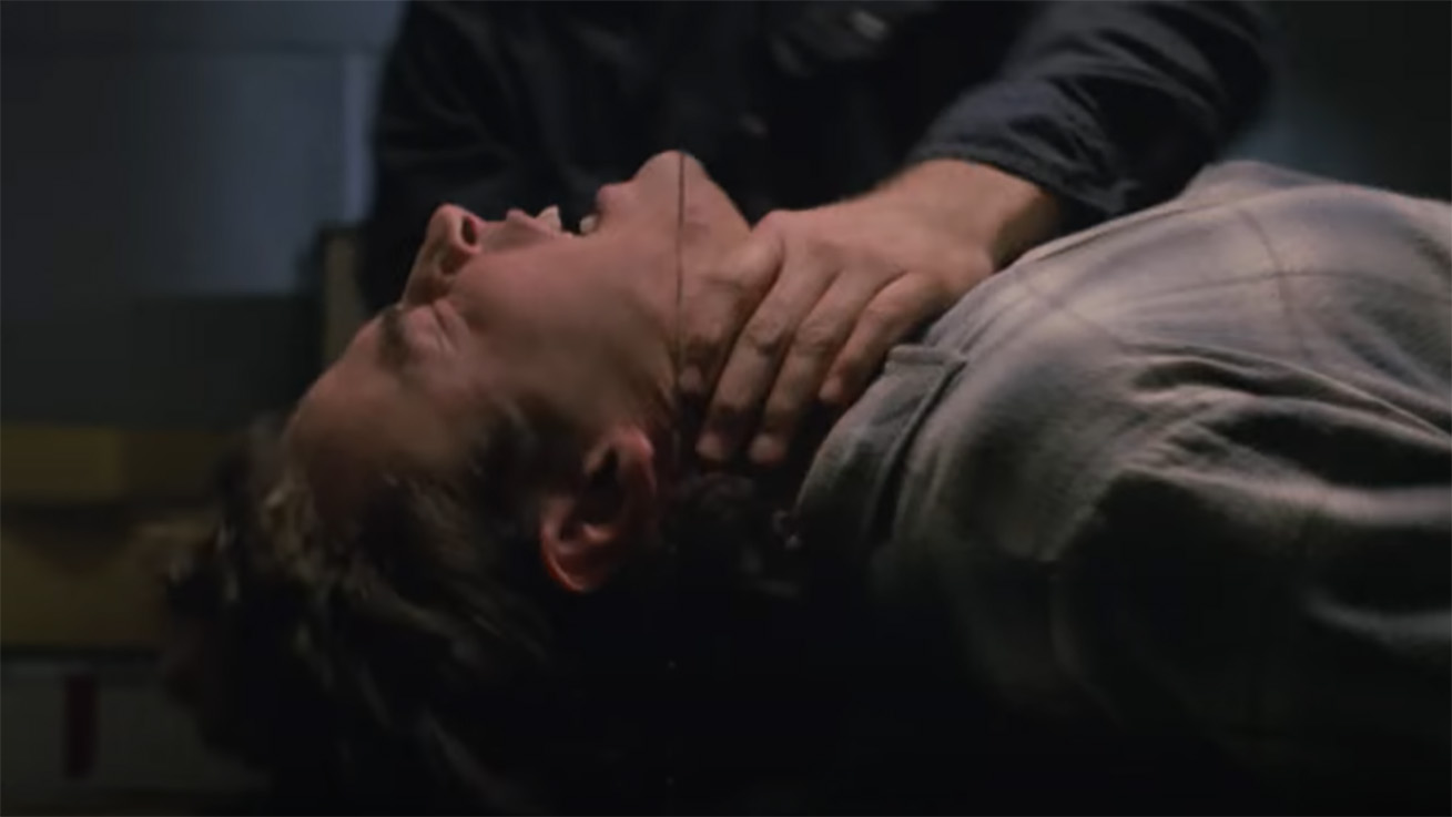 A man getting held down on a table in front of a band saw in Intruder (1989)