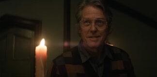 Hugh Grant as Mr. Reed holding a candle in Heretic