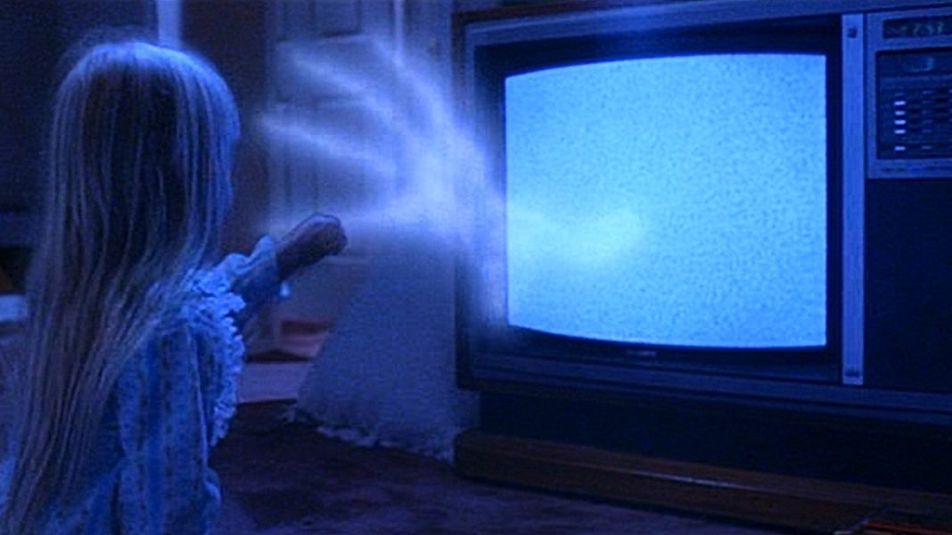 A little girl being grabbed by a ghostly hand from a TV in Poltergeist (1982)