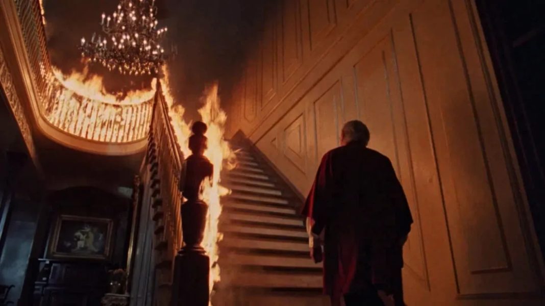George C. Scott looking up a flaming staircase in The Changeling (1980)