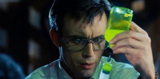Herbert West (Jeffrey Combs) gets a dose of the glowing reanimating reagent in a syringe in Re-Animator