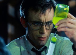 Herbert West (Jeffrey Combs) gets a dose of the glowing reanimating reagent in a syringe in Re-Animator