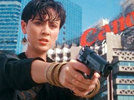 A woman points a gun at someone in She Shoots Straight (1990)