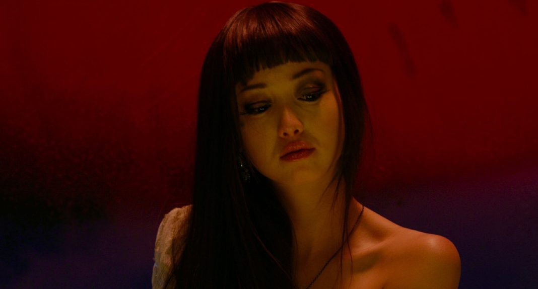 Against a red and purple background, a woman looks down in Helter Skelter (2012)