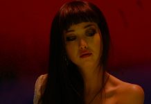 Against a red and purple background, a woman looks down in Helter Skelter (2012)