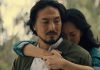 Keiko Miura (Mari Yamamoto) hugs Hiroshi Randa (Takehiro Hira) from behind while crying in Legacy of Monsters Season 2, Episode 5 'Furusato'