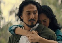 Keiko Miura (Mari Yamamoto) hugs Hiroshi Randa (Takehiro Hira) from behind while crying in Legacy of Monsters Season 2, Episode 5 'Furusato'