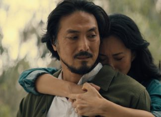 Keiko Miura (Mari Yamamoto) hugs Hiroshi Randa (Takehiro Hira) from behind while crying in Legacy of Monsters Season 2, Episode 5 'Furusato'