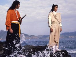 Two men stand on a rock on the seashore in DUEL TO THE DEATH