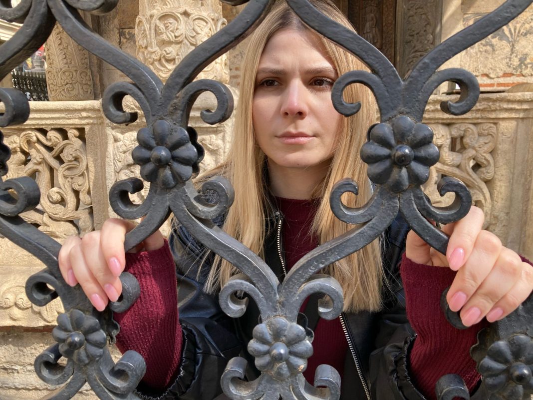 A woman stands at a gate in Transylvania Tapes