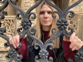 A woman stands at a gate in Transylvania Tapes