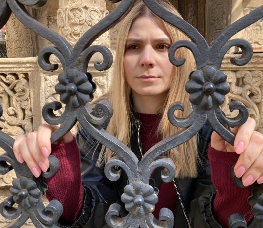 A woman stands at a gate in Transylvania Tapes