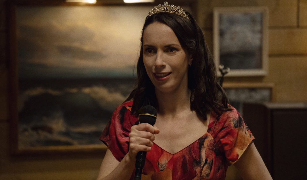 Patricia holds a mic while talking at her party in Widows Bay Season 1