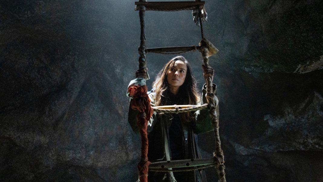 Tabitha looks around a cave while climbing a ladder in the From Season 4 finale