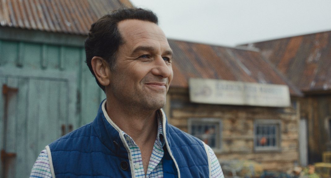 Tom Loftis smiles as he looks around outside in Widows Bay Season 1 Tom Loftis smiles as he looks around outside in Widows Bay Season 1