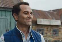 Apple TV’s Breakout Horror-Comedy Scores Early Season 2 Renewal Tom Loftis smiles as he looks around outside in Widows Bay Season 1