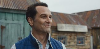 Apple TV’s Breakout Horror-Comedy Scores Early Season 2 Renewal Tom Loftis smiles as he looks around outside in Widows Bay Season 1