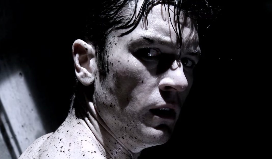 A man, covered in dark liquid, turns around in Tetsuo The Bullet Man