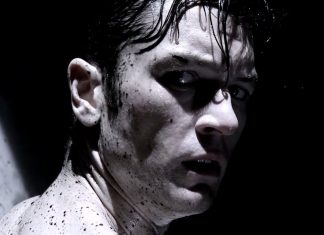 A man, covered in dark liquid, turns around in Tetsuo The Bullet Man