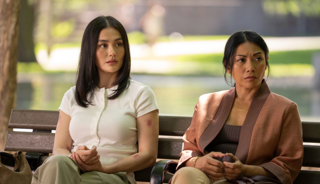 AGNEZ MO as Lila Hoth, Anggun as Amisha sit on a bench after a fight in Prime Video's Reacher Season 4