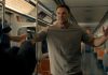 Reacher holds his hands up at gunpoint on a subway in Reacher Season 4