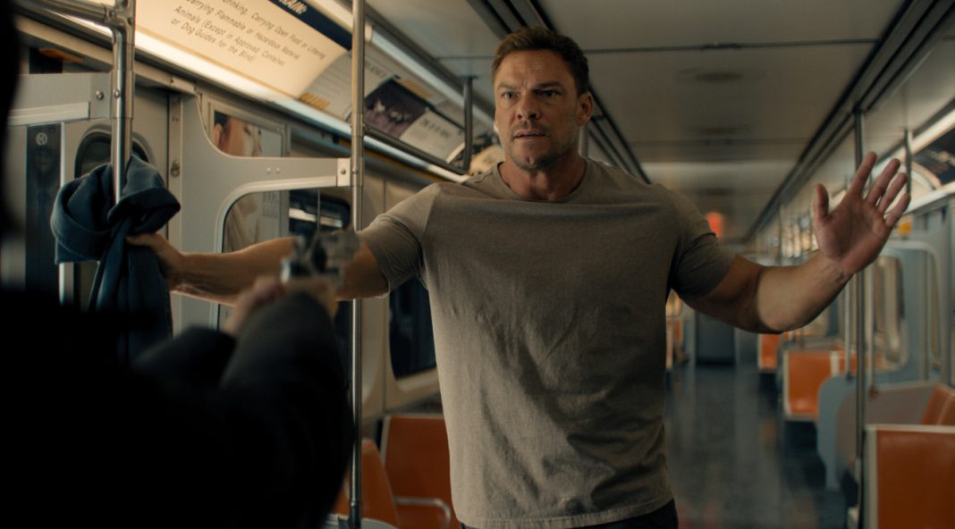 Reacher holds his hands up at gunpoint on a subway in Reacher Season 4 Reacher holds his hands up at gunpoint on a subway in Reacher Season 4