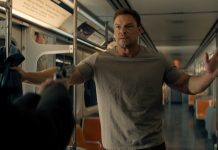 Reacher holds his hands up at gunpoint on a subway in Reacher Season 4