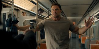 Reacher holds his hands up at gunpoint on a subway in Reacher Season 4