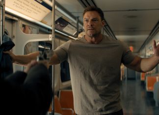 Reacher holds his hands up at gunpoint on a subway in Reacher Season 4