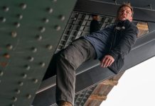 Reacher holds onto a beam under a bridge in Reacher Season 4
