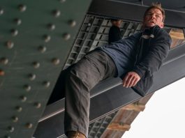 Reacher holds onto a beam under a bridge in Reacher Season 4
