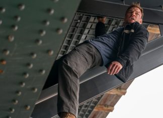 Reacher holds onto a beam under a bridge in Reacher Season 4