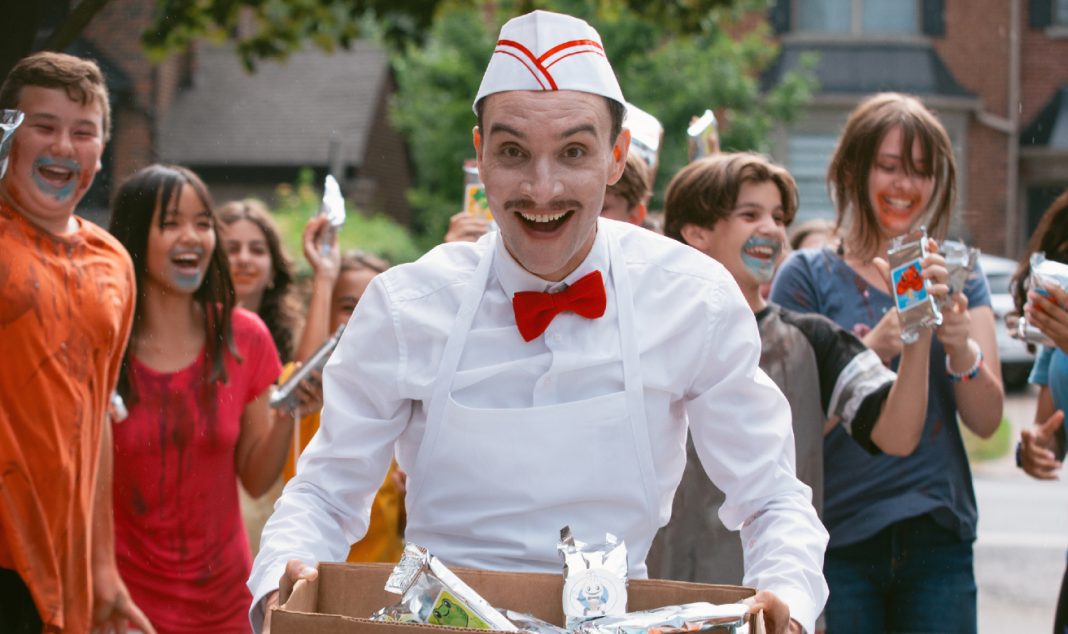 The Ice Cream Man smiles while giving children ice cream in Eli Roth's Ice Cream Man