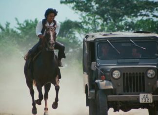 A man on horseback rides next to a Jeep in Roaring Fire 1981