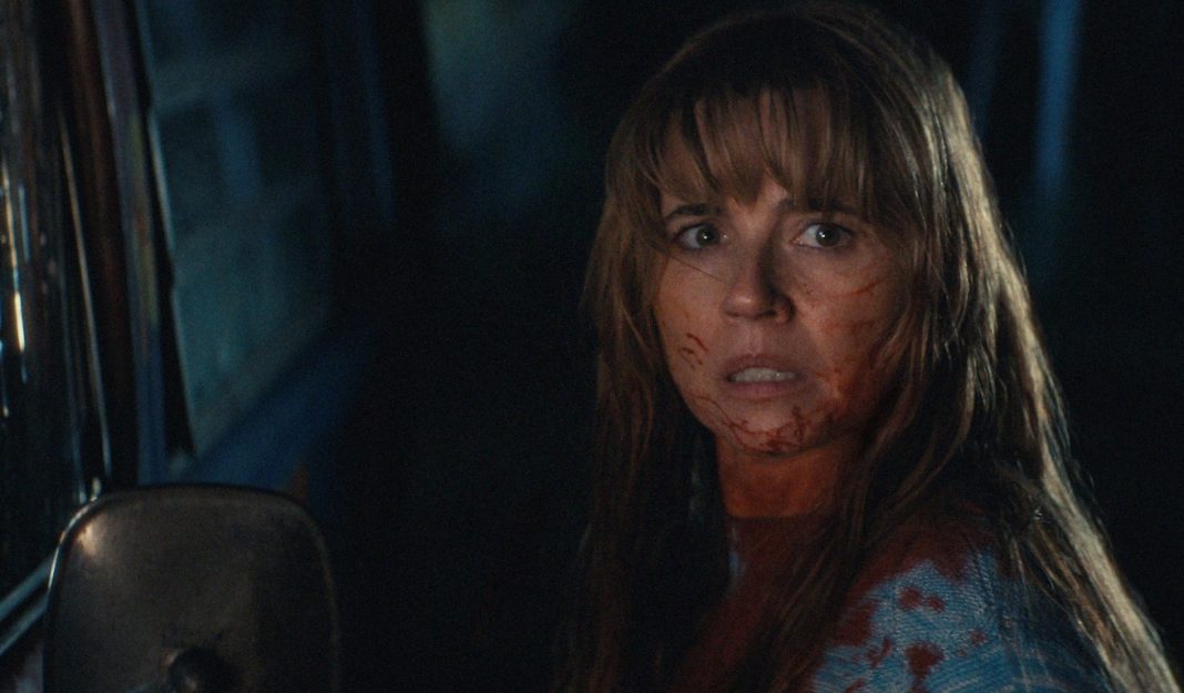 Pam Voorhees (Linda Cardellini) stands next to a truck, covered in blood, in Crystal Lake