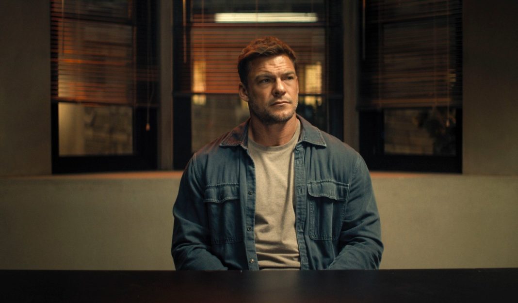 Reacher sits at a police desk in Reacher Season 4 Reacher sits at a police desk in Reacher Season 4