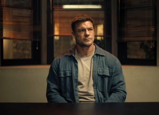 Reacher sits at a police desk in Reacher Season 4